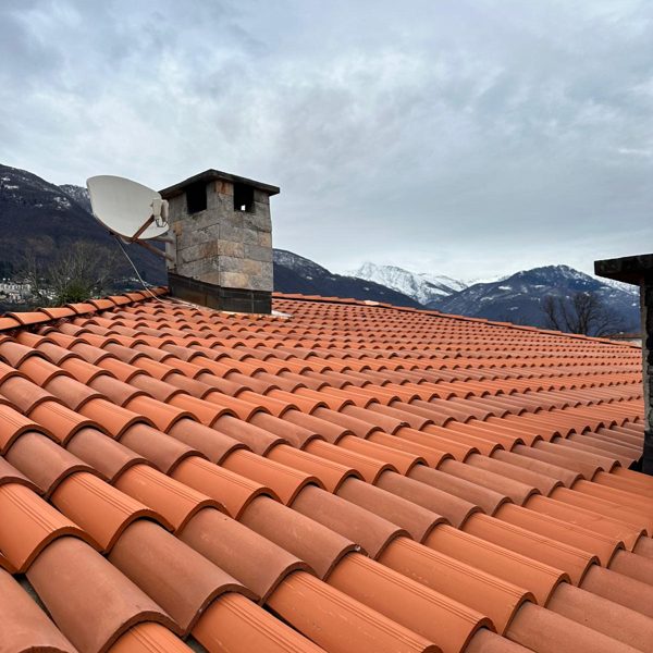 Nachher: dasselbe Dach komplett neu eingedeckt, dahinter Kamin und Berge